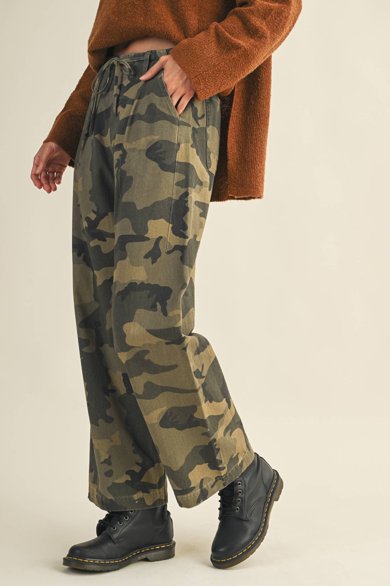 Person wearing camouflage pants and brown sweater.