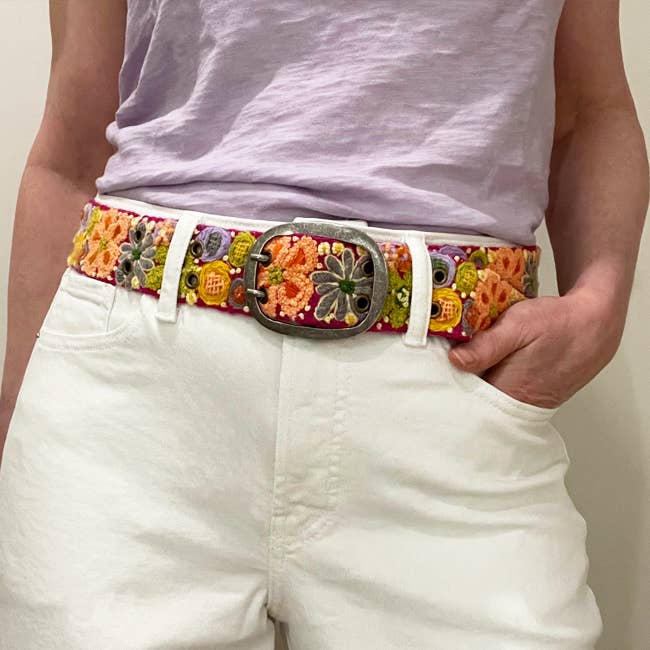 Person wearing floral embroidered belt.
