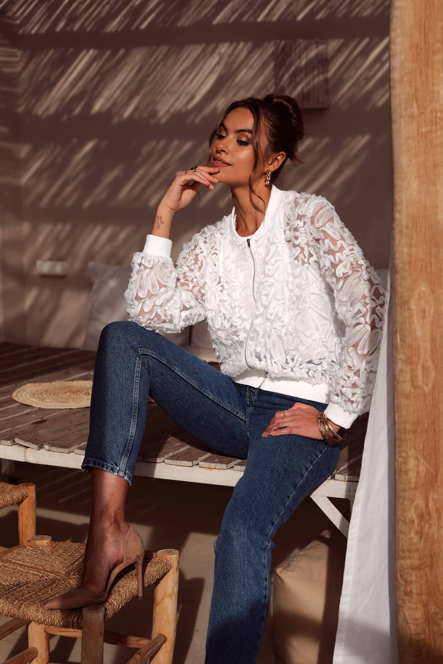 Woman in white lace jacket and jeans.