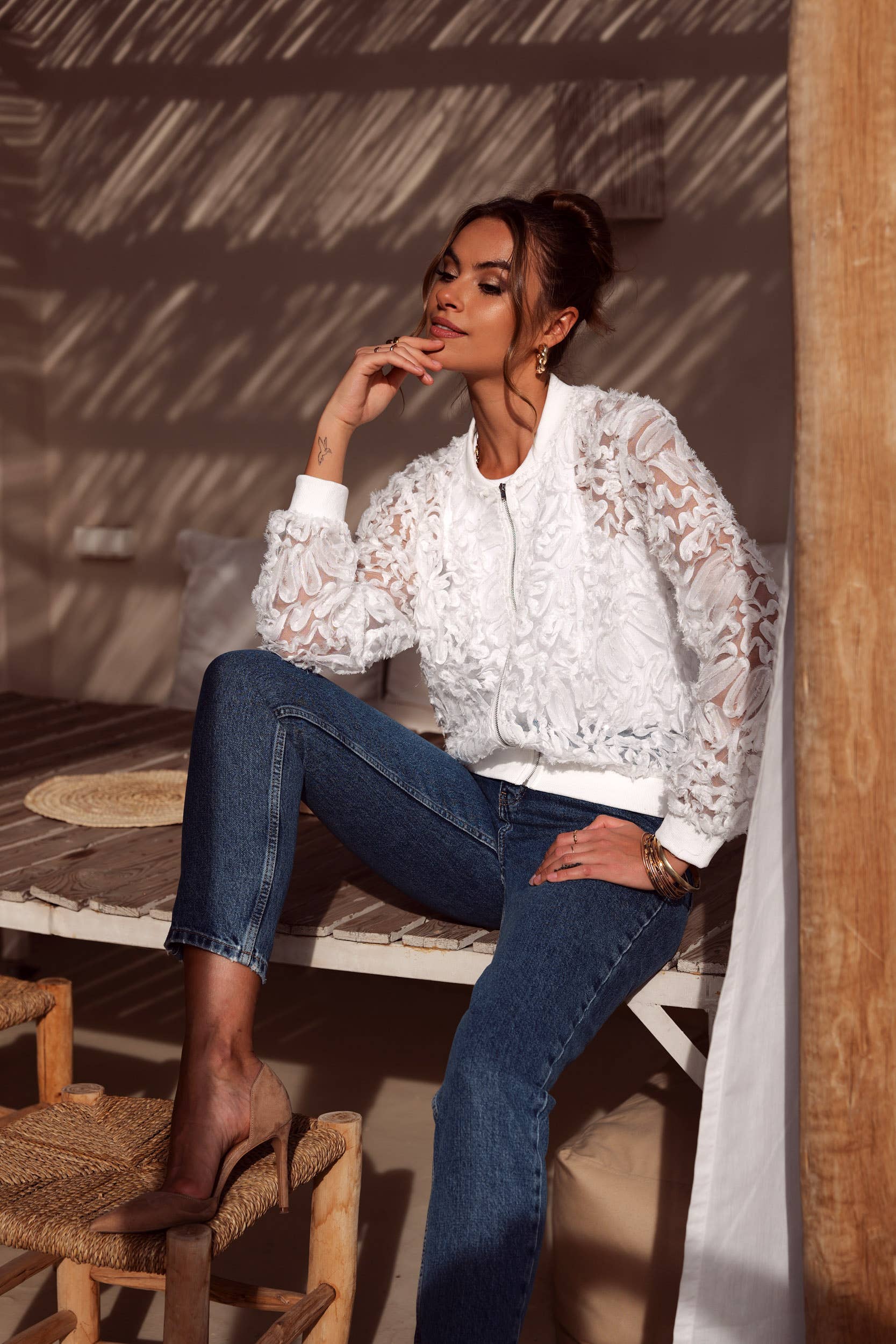 Woman in white lace jacket and jeans.