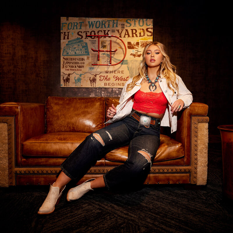 Woman in denim and red top on a leather couch.