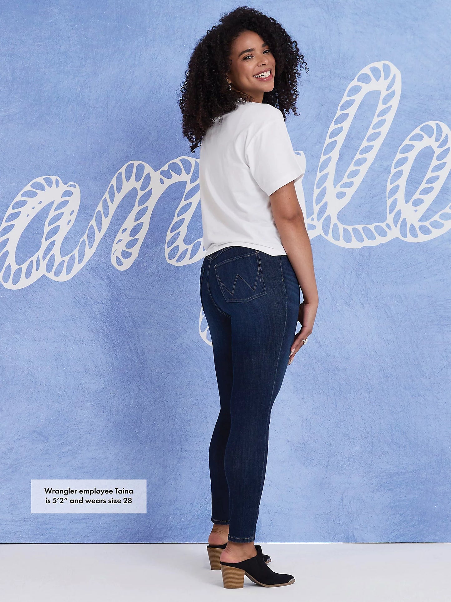 Woman in jeans and a white shirt smiling.