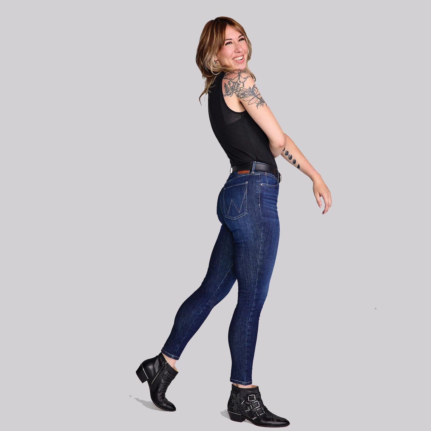 Woman in jeans and black top smiling.