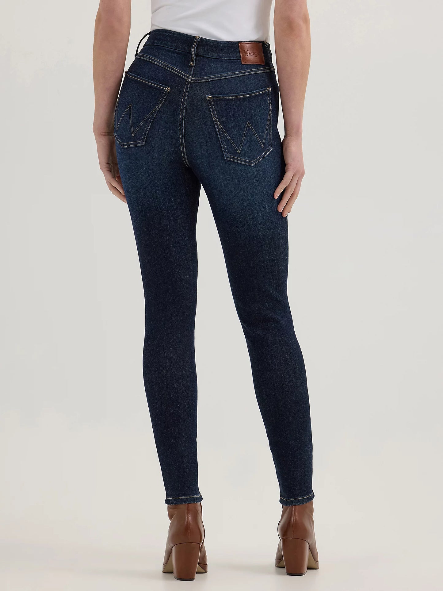 Woman wearing dark blue jeans and brown boots.
