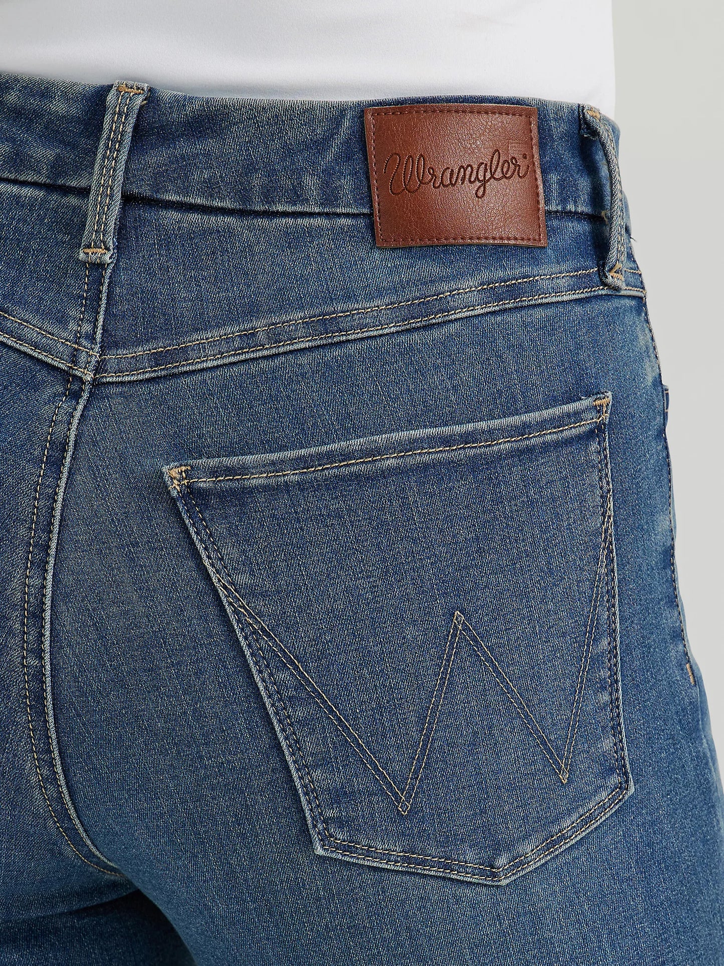 Close-up of blue jeans with a Wrangler leather patch.