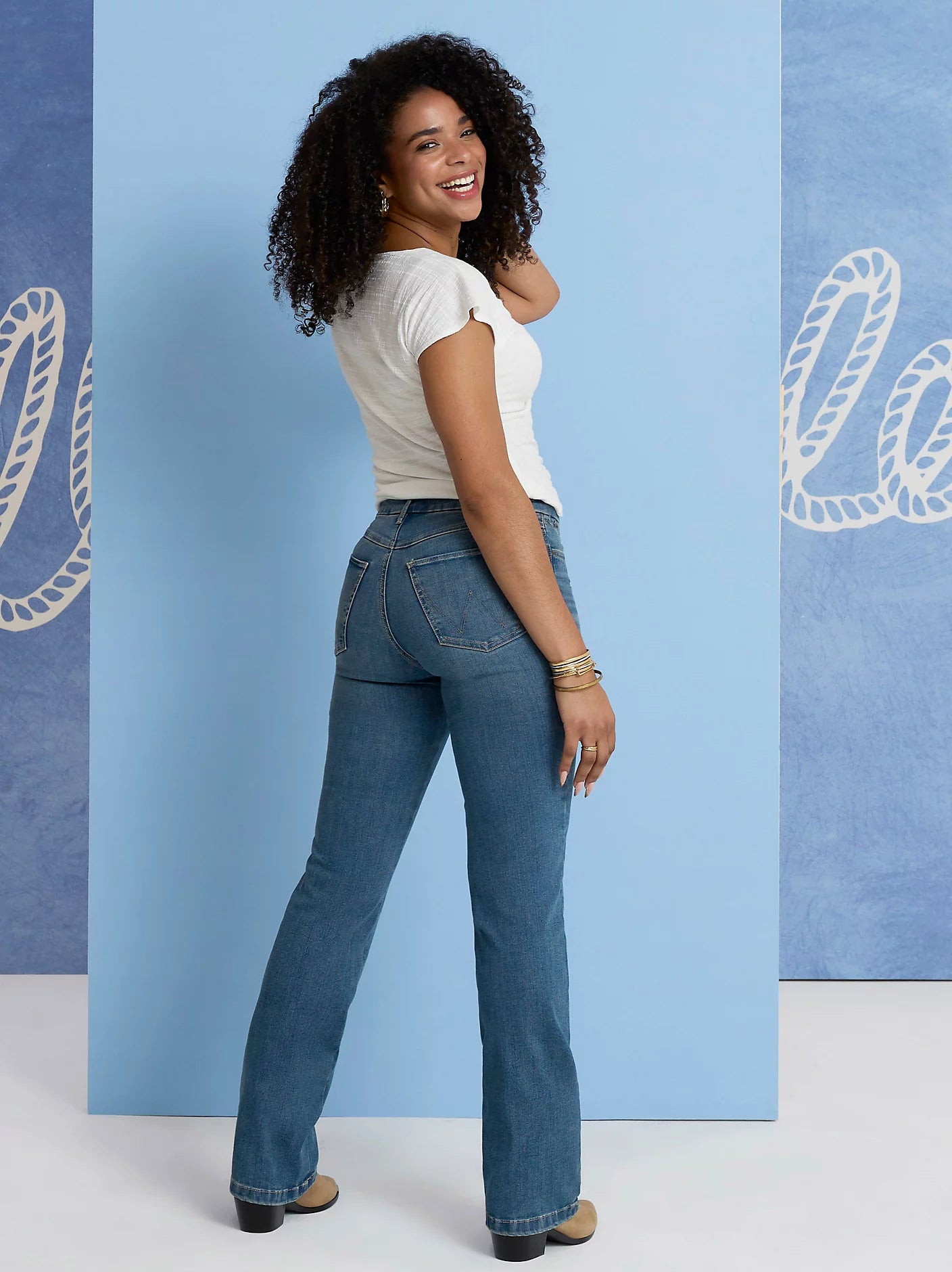 Woman in jeans and white top, standing.
