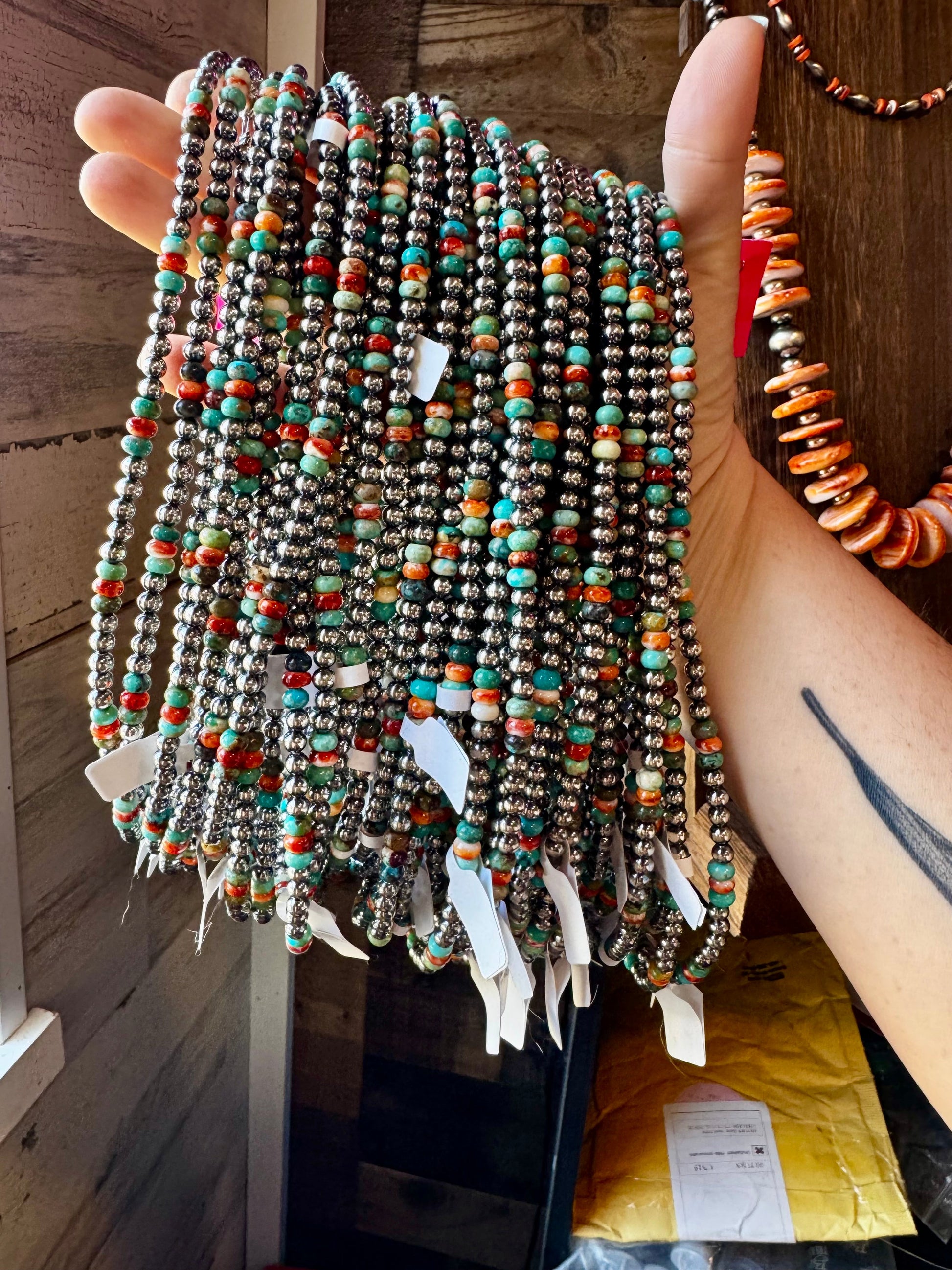 Hand holding turquoise & silver beaded necklaces, 12EBC273-ABF0