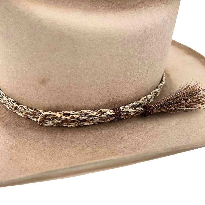 Tan cowboy hat with decorative band and tassel.