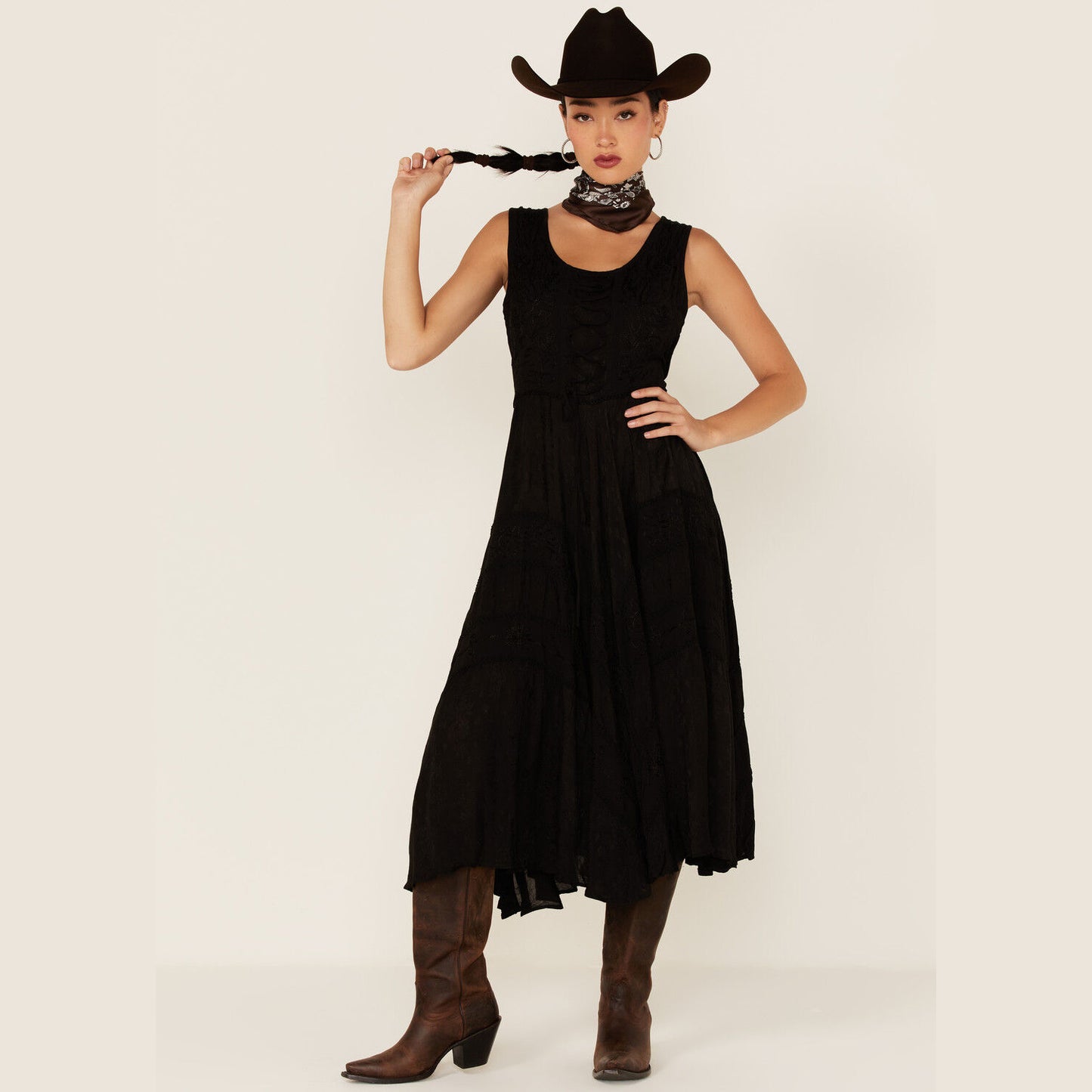 Woman in black dress, cowboy hat, and boots.