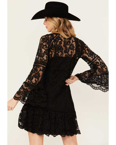 Woman wearing a black lace dress and hat.