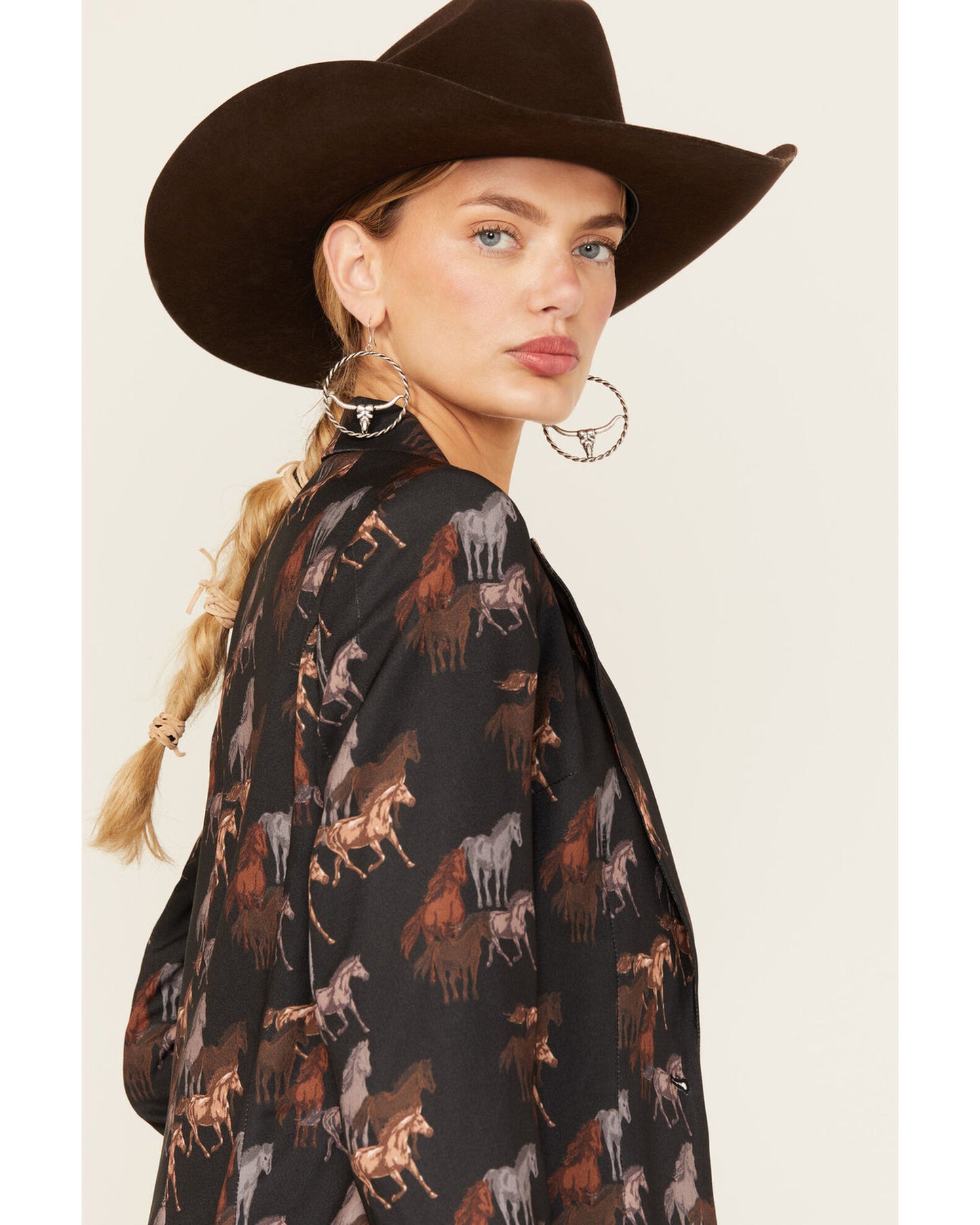 Woman wearing cowboy hat and horse-print jacket.