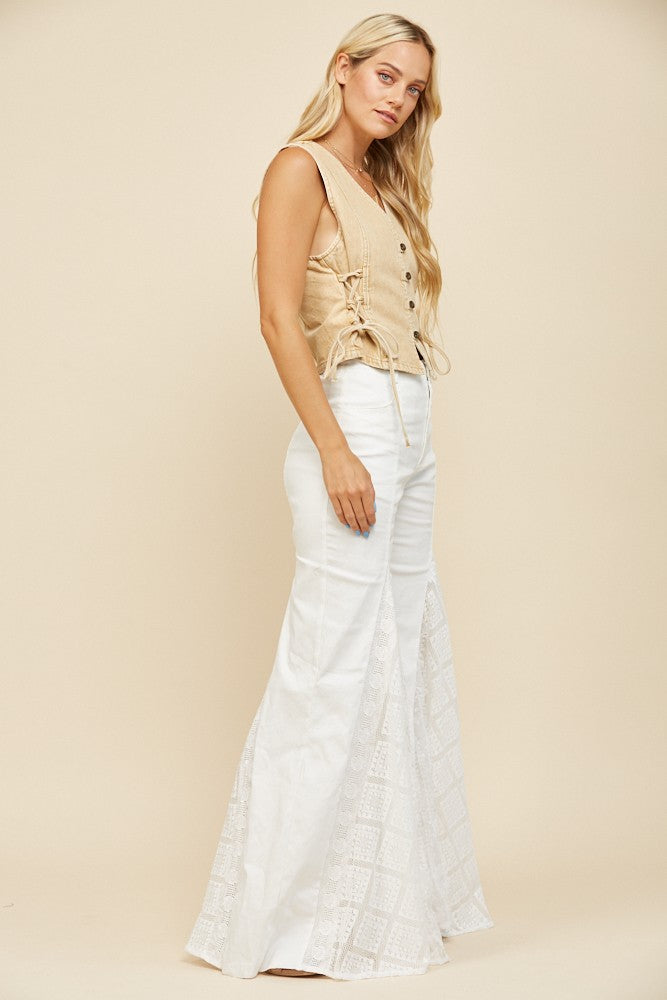 Woman in tan vest and white pants.
