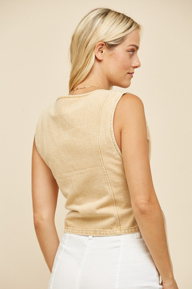 Woman wearing a tan sleeveless top, turned to the side.