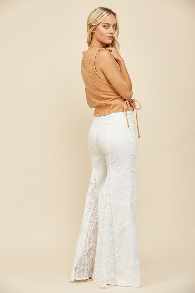 Woman in tan top and white flared pants.