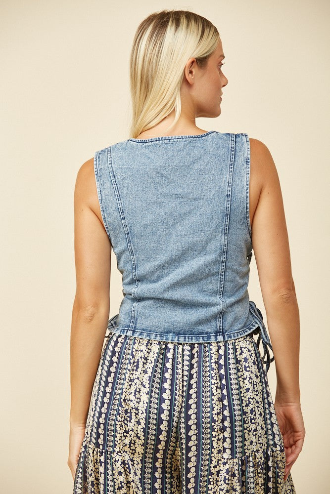 Woman wearing denim vest and patterned pants.