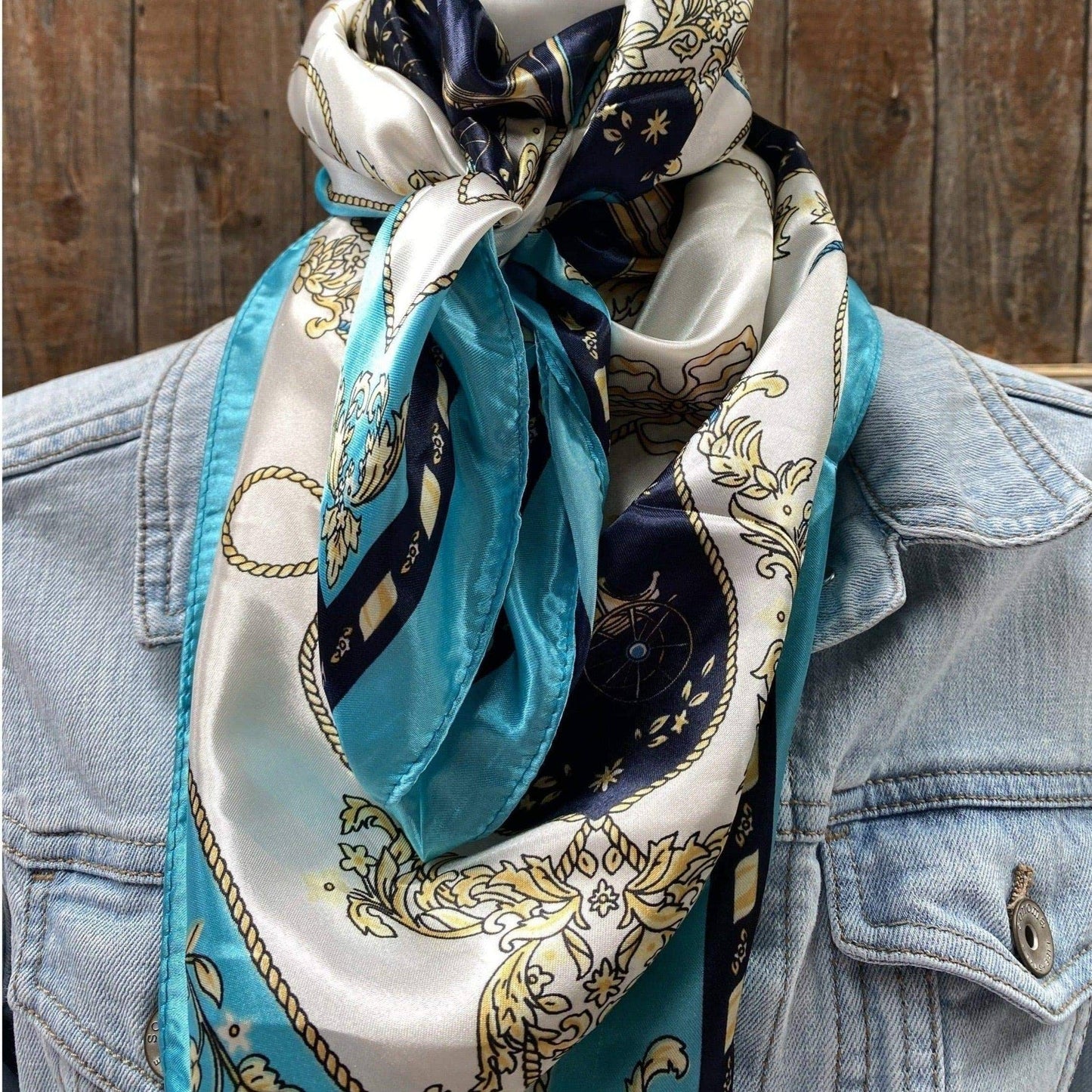 Silk scarf with blue, white, and gold nautical pattern on denim jacket.