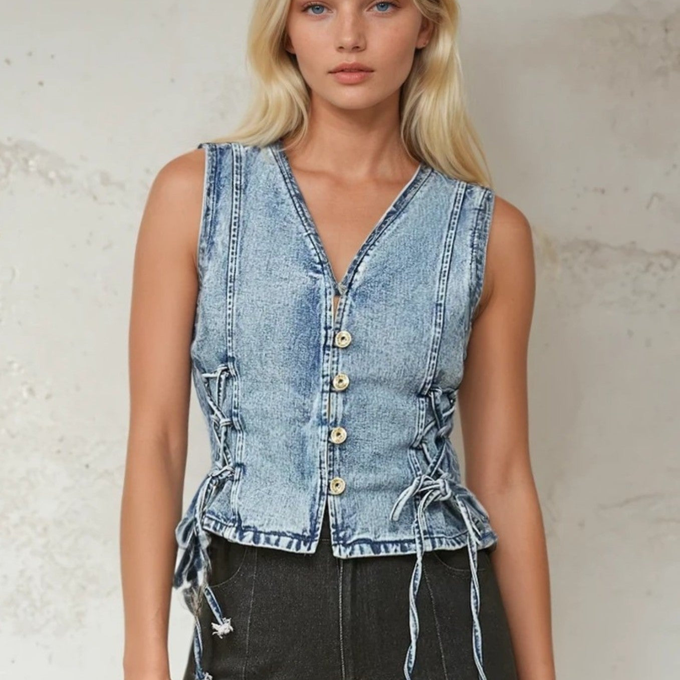 Woman wearing a denim vest with lace-up sides.