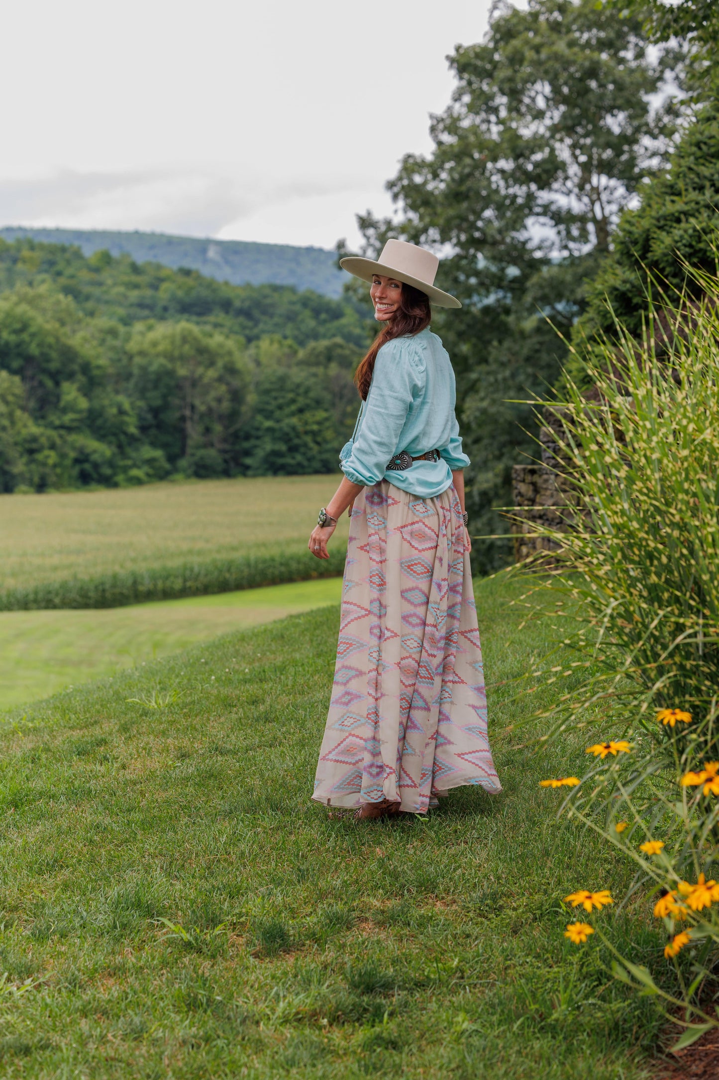 Woman in Toni Shirt and Sunny Skirt on a grassy hillside.