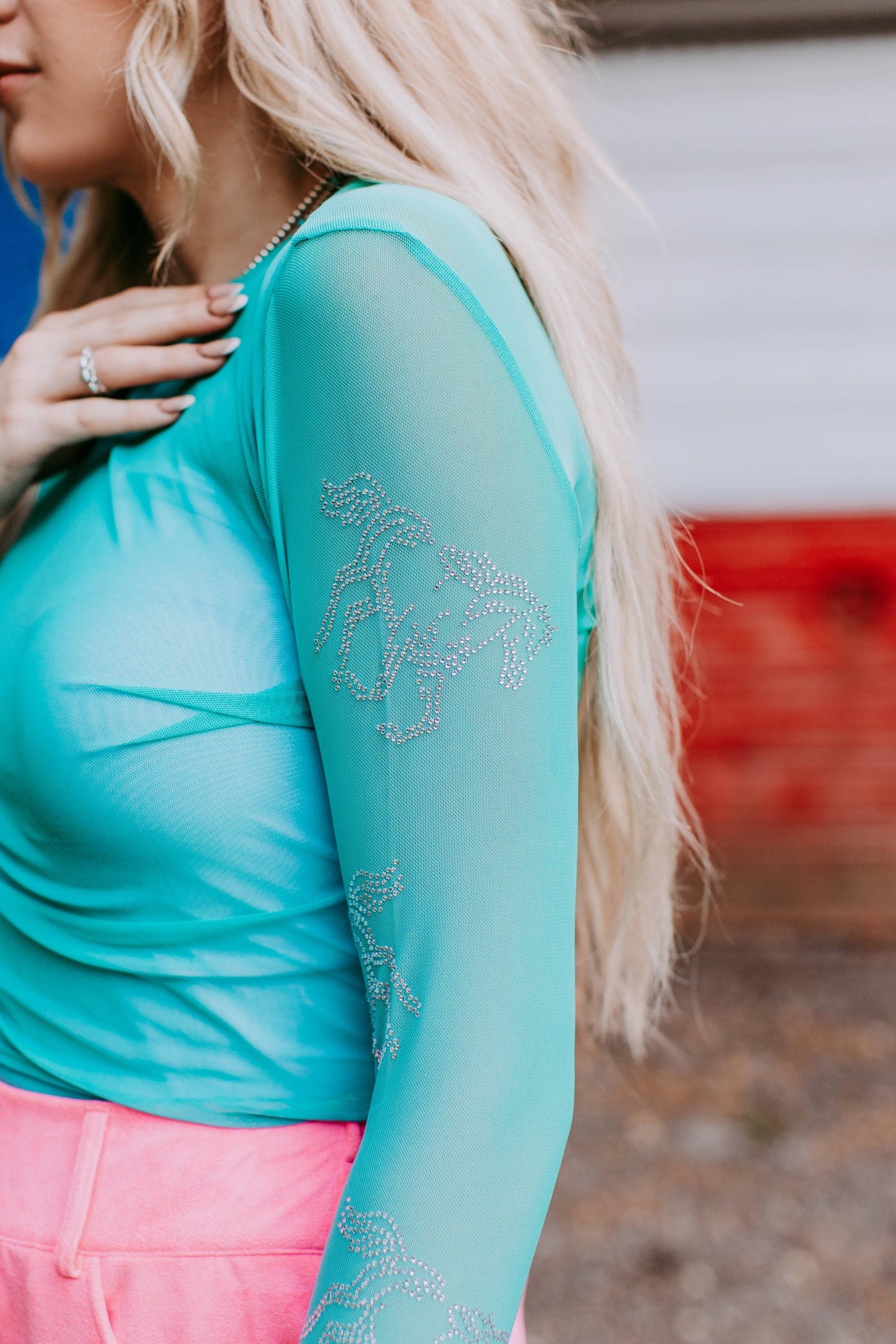 Woman wearing turquoise top with long sleeve.