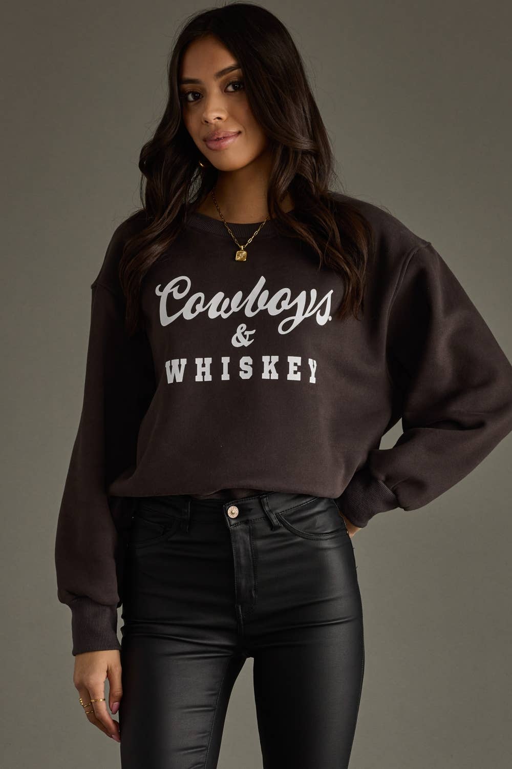 Woman wearing a brown Cowboys & Whiskey sweatshirt.