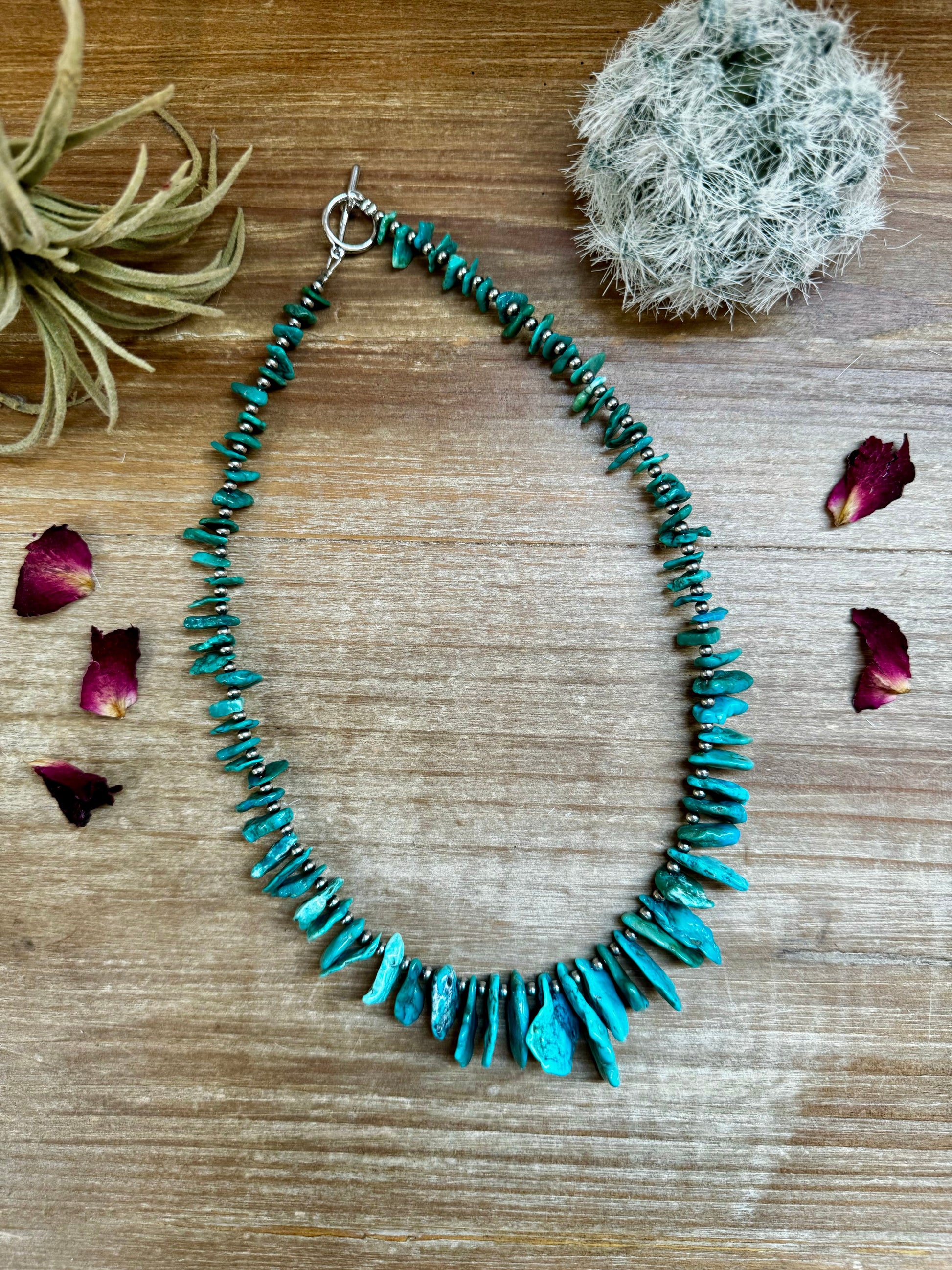 Turquoise necklace (4C234A9C-D30B) with toggle clasp, on wooden surface.
