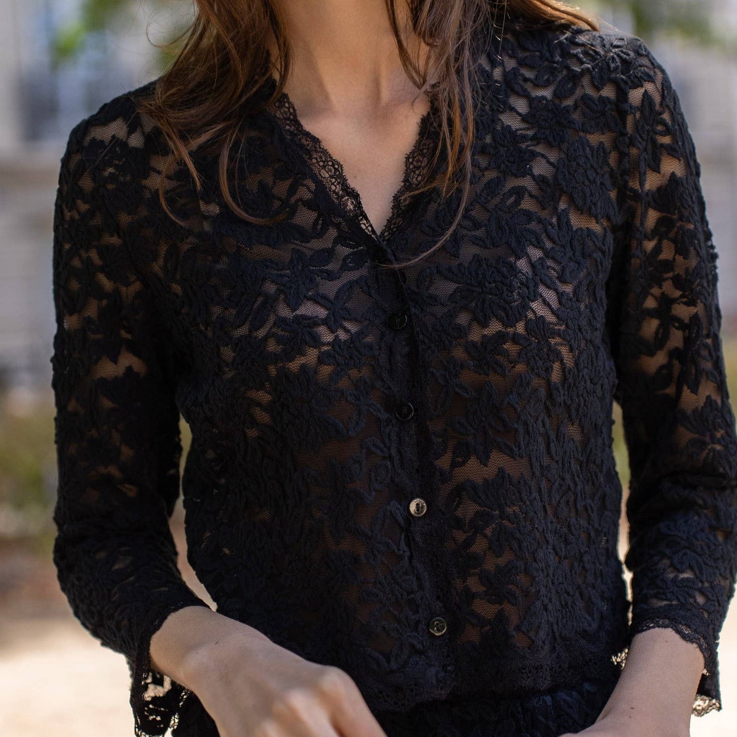 Woman wearing black lace button-up shirt.