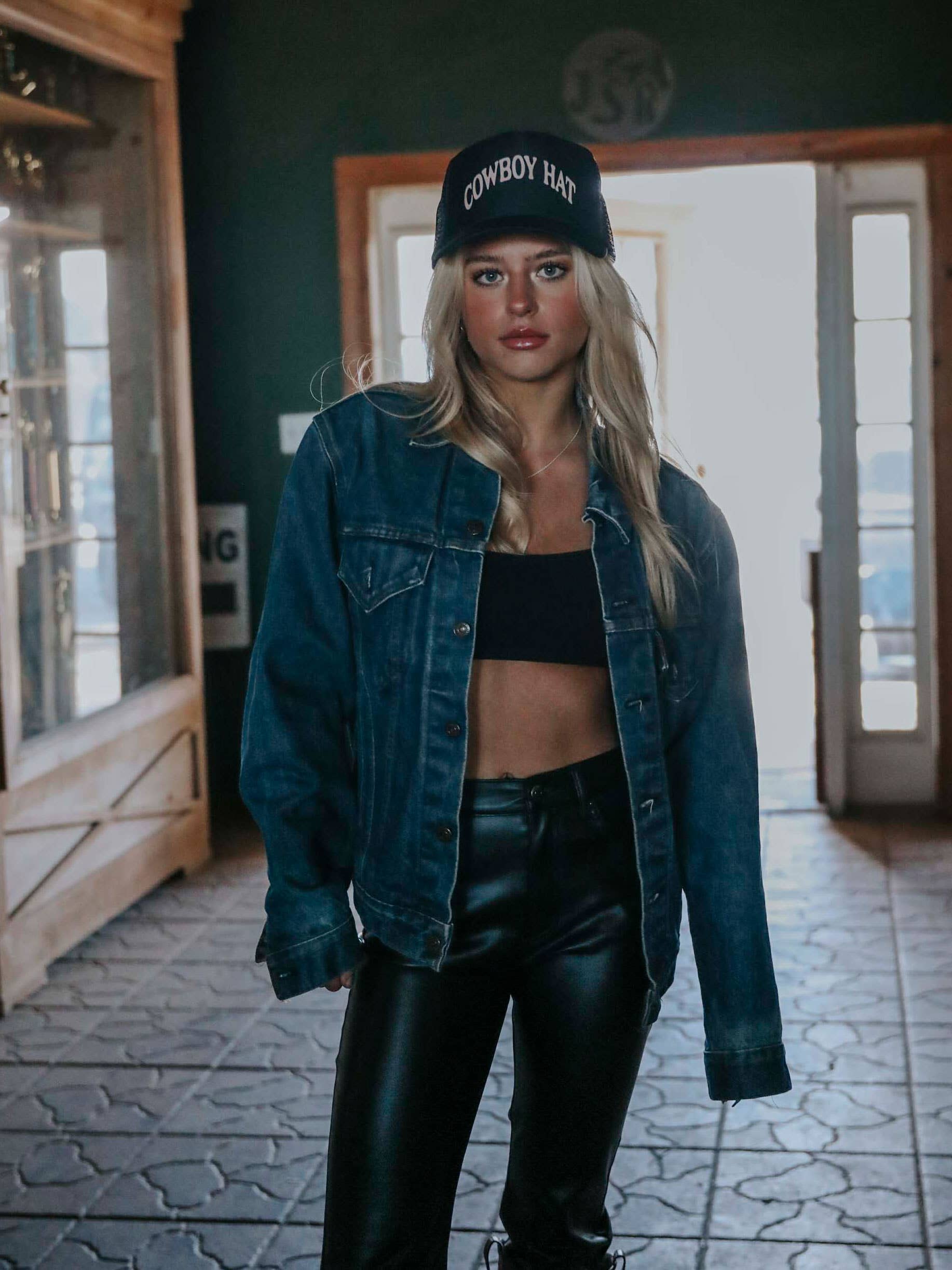 Woman in jean jacket and hat.