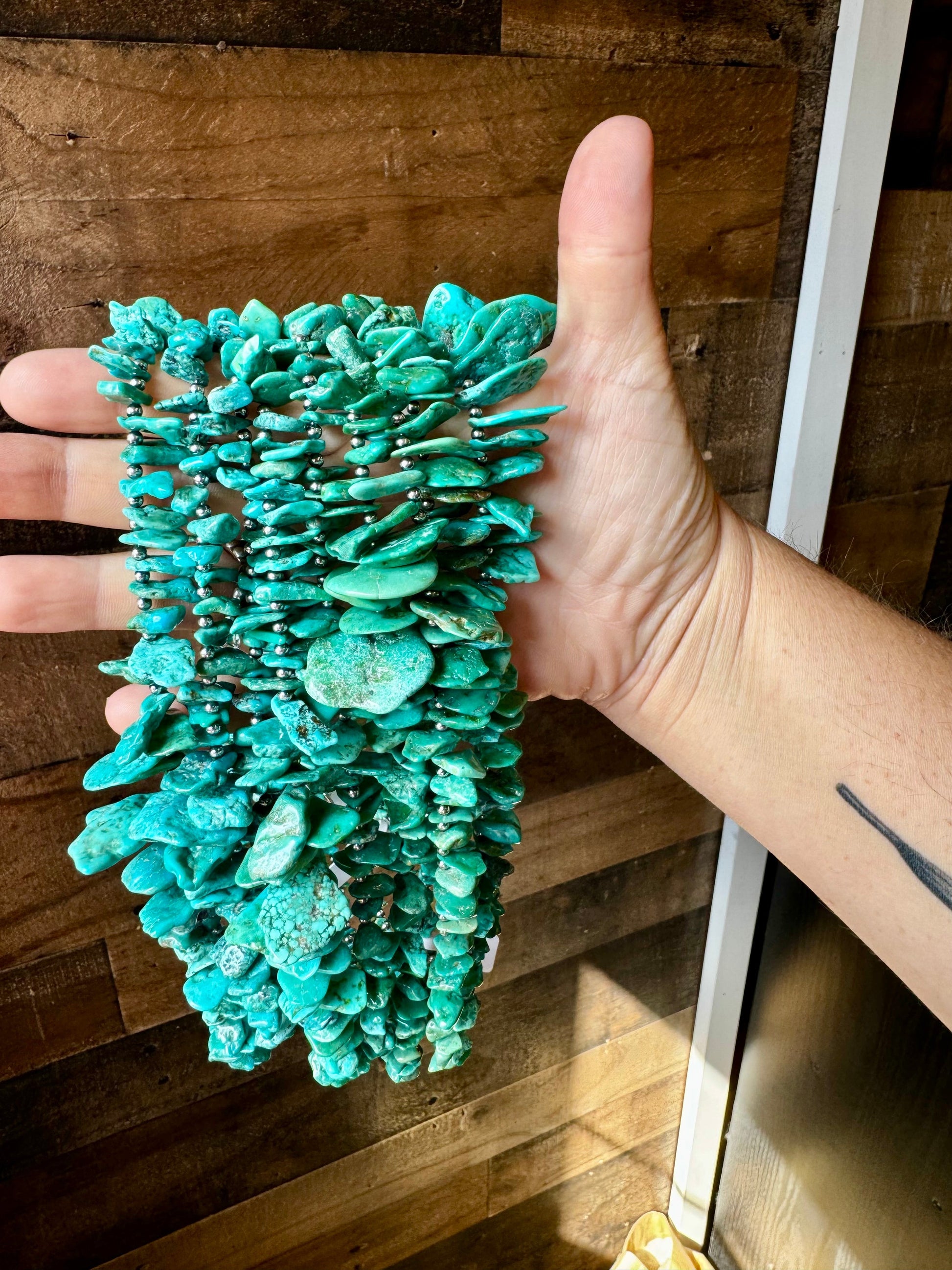 Turquoise stone bracelet held in hand (5F9B7F09-7632-4DB4)