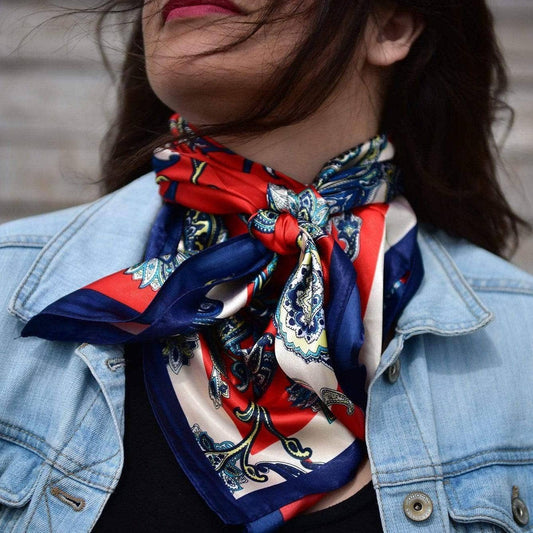 Woman wearing a patterned red, white, and blue scarf and denim jacket.