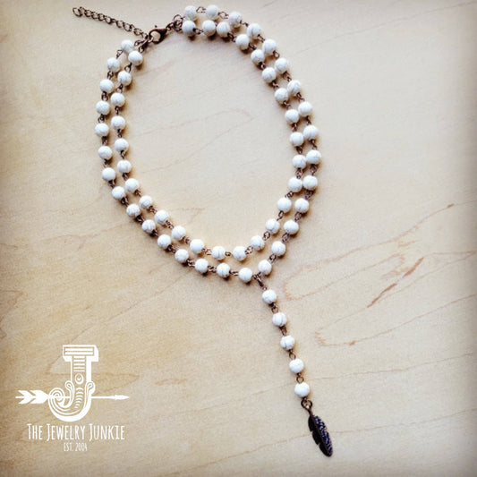 White beaded necklace with feather charm.