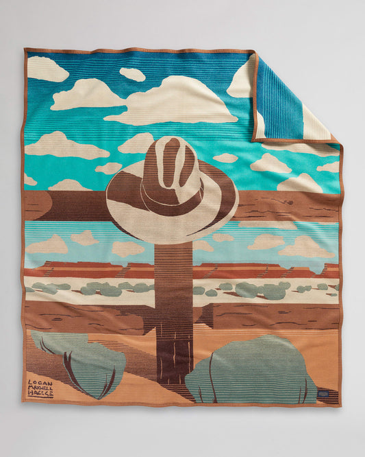 Blanket with desert landscape and cowboy hat.