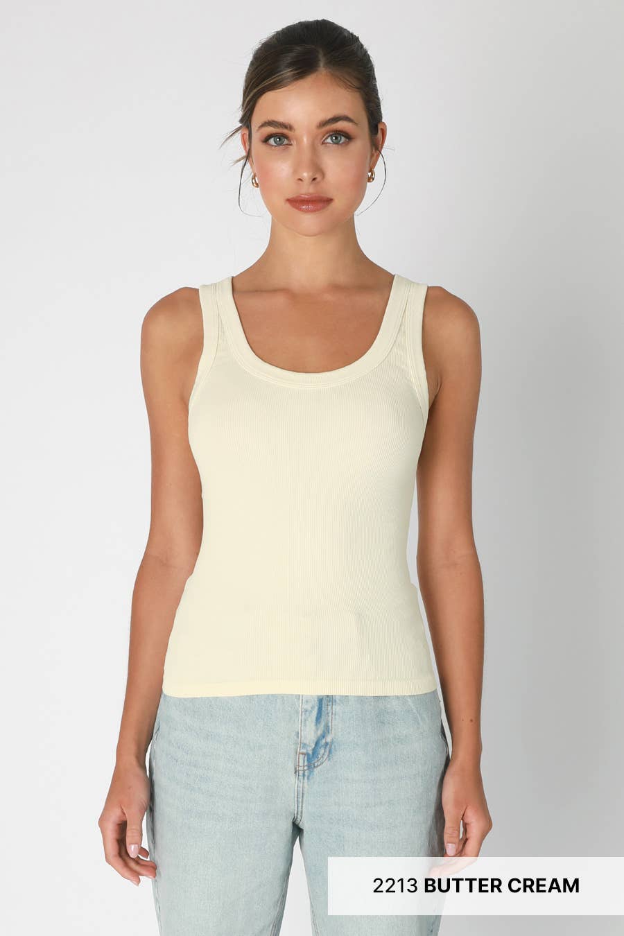 Woman wearing a cream ribbed tank top and jeans.