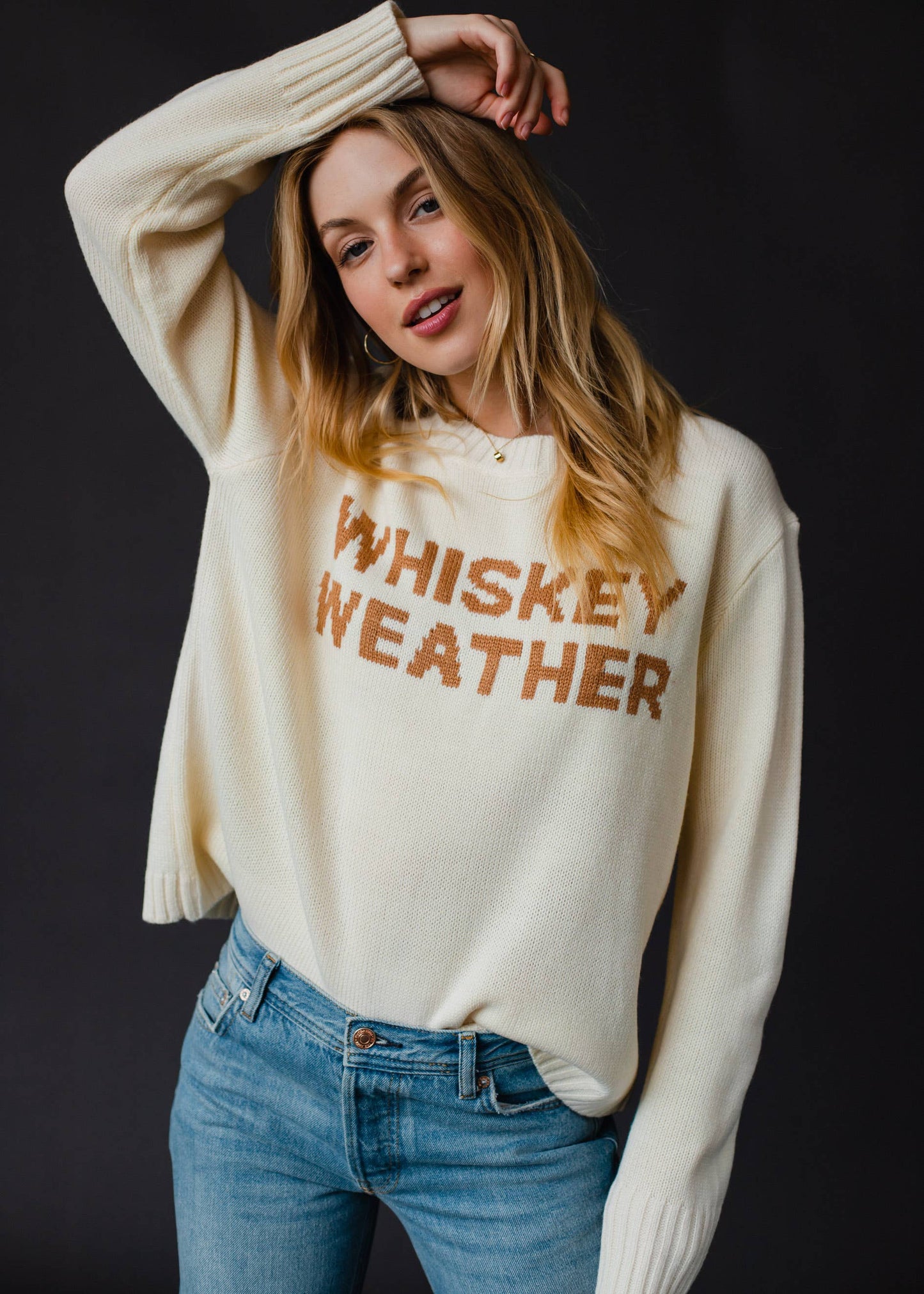 Woman in cream sweater and jeans.