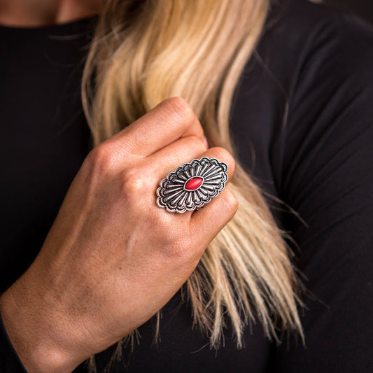 Woman's hand wearing a large, silver ring with a red center stone.