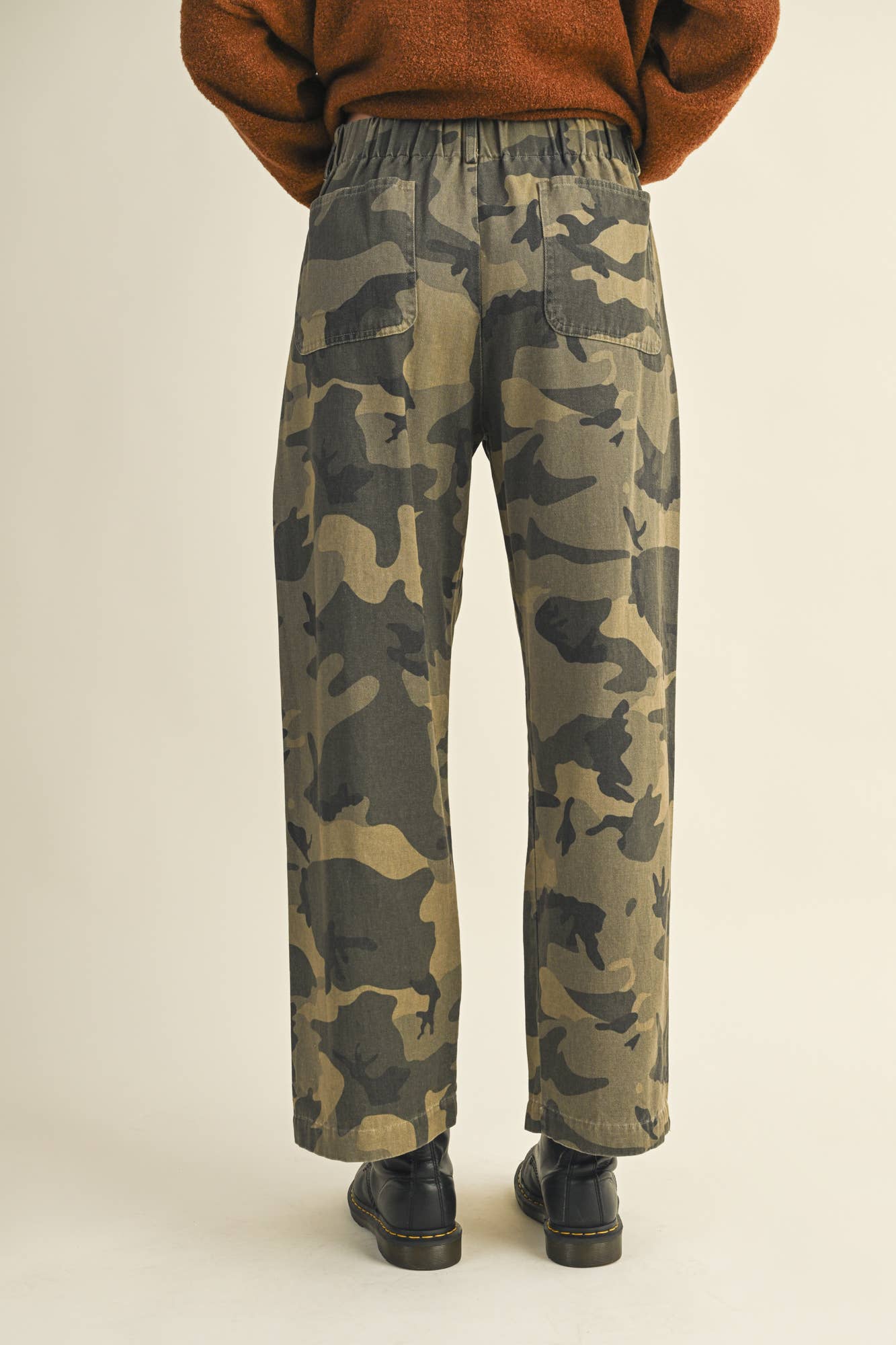 Person wearing camouflage pants and brown sweater.