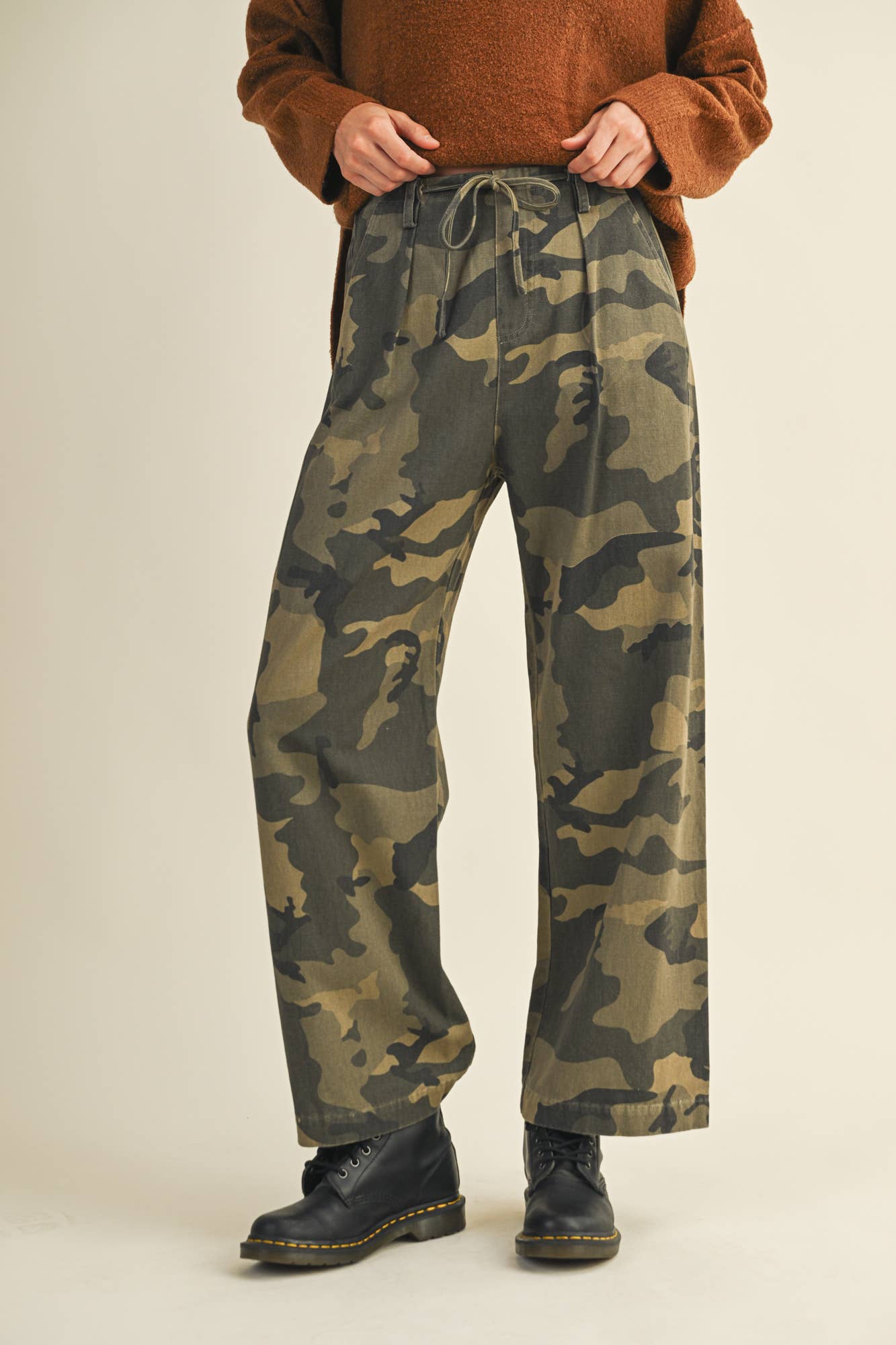 Person wearing camouflage pants and brown sweater.