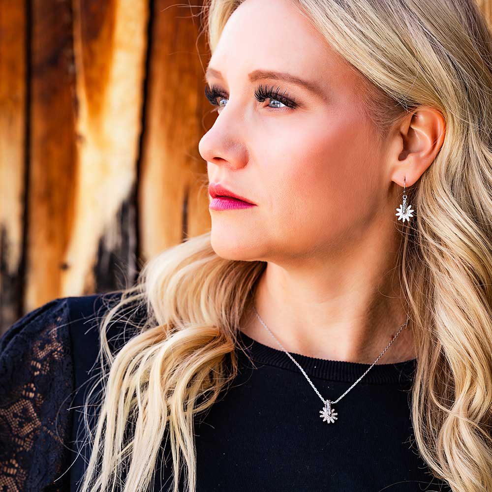 Blonde woman wearing daisy pendant and earrings