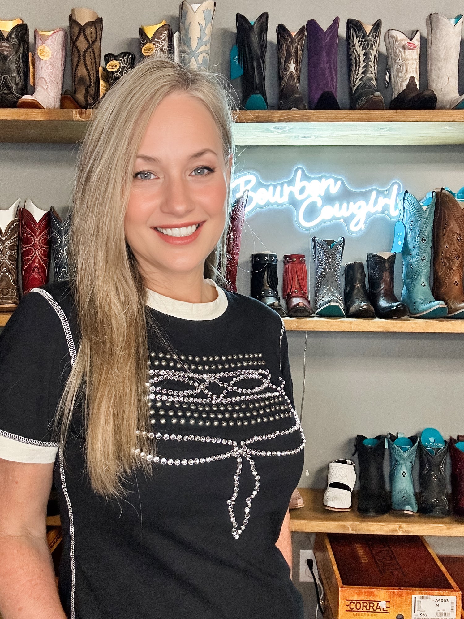 Woman smiling in front of cowboy boots, Bourbon Cowgirl
