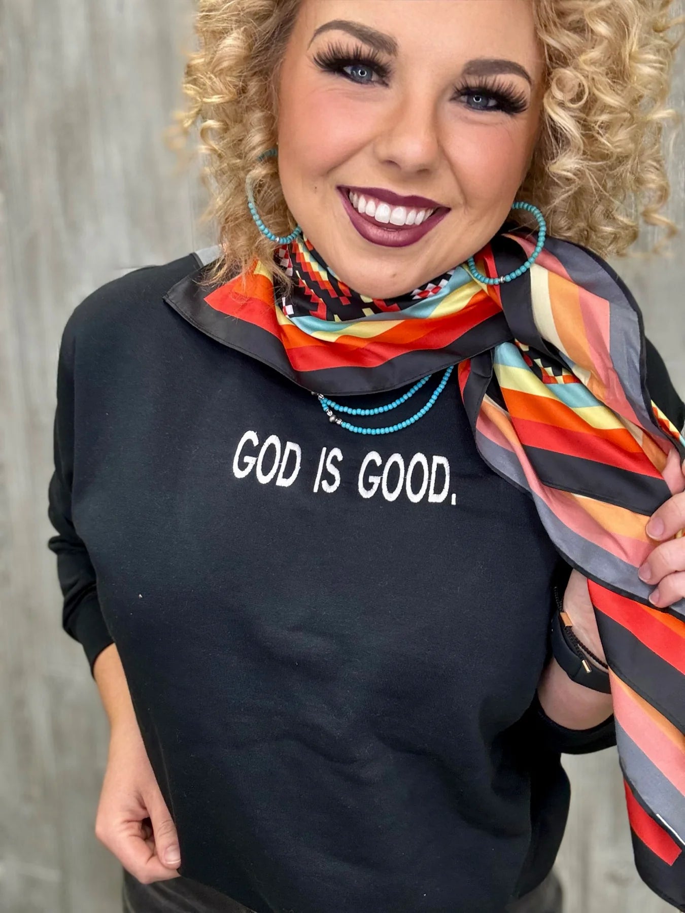 Woman in God is Good sweatshirt with colorful scarf