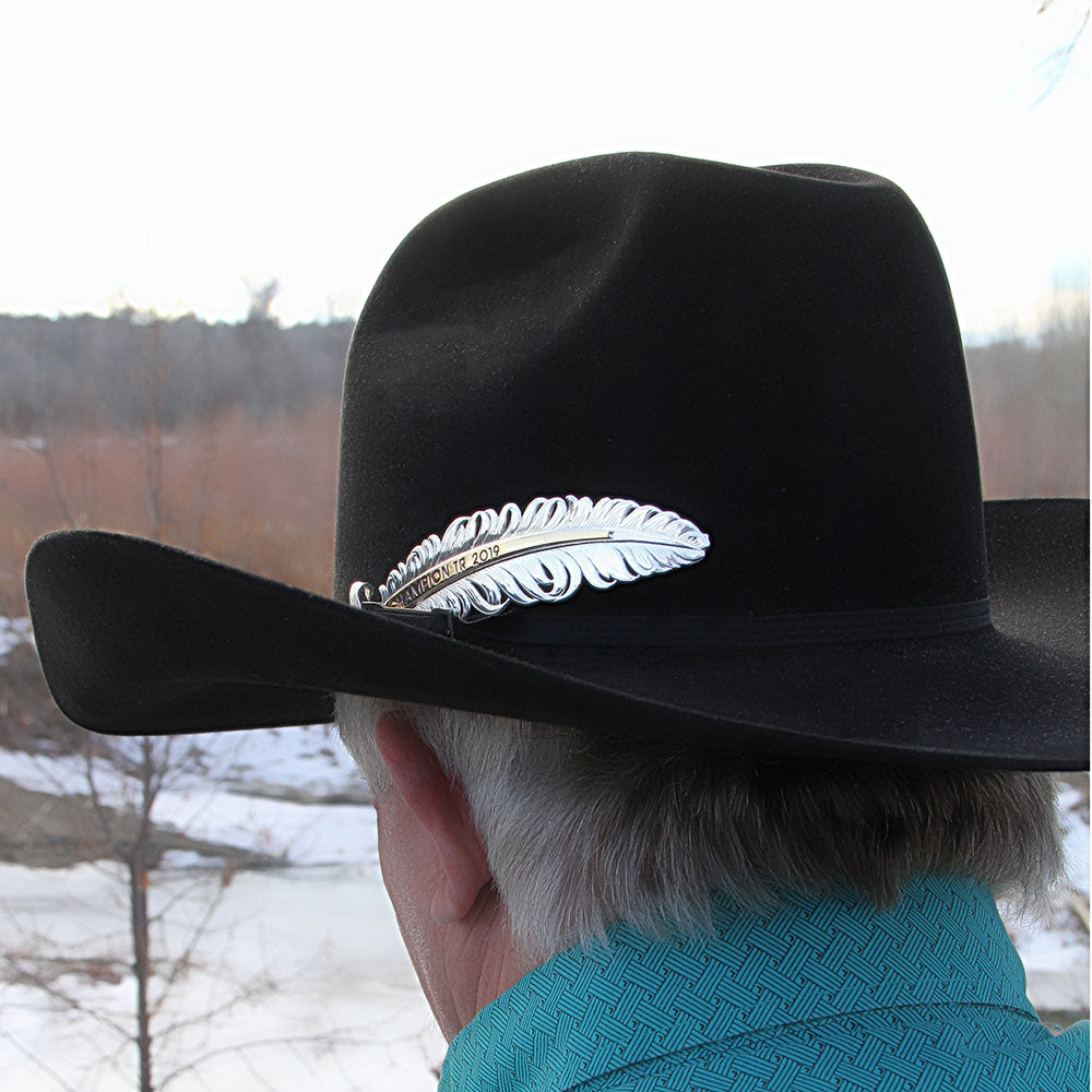 Black cowboy hat with silver feather pin.