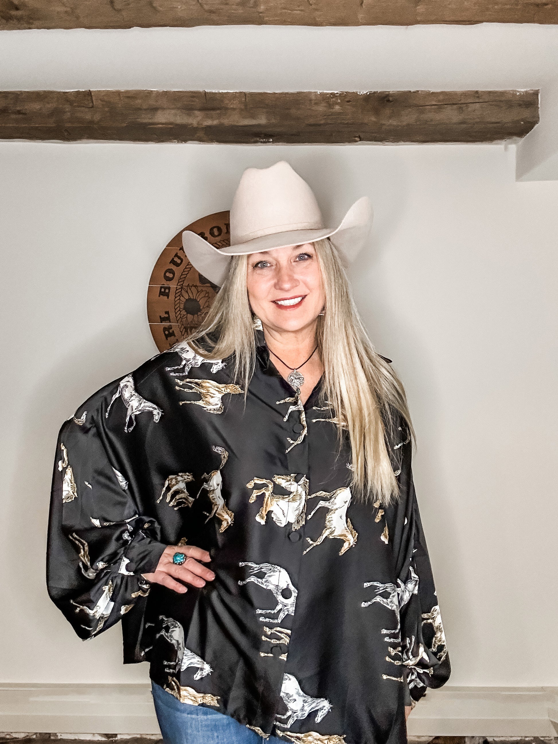 Woman in cowboy hat and horse print shirt.