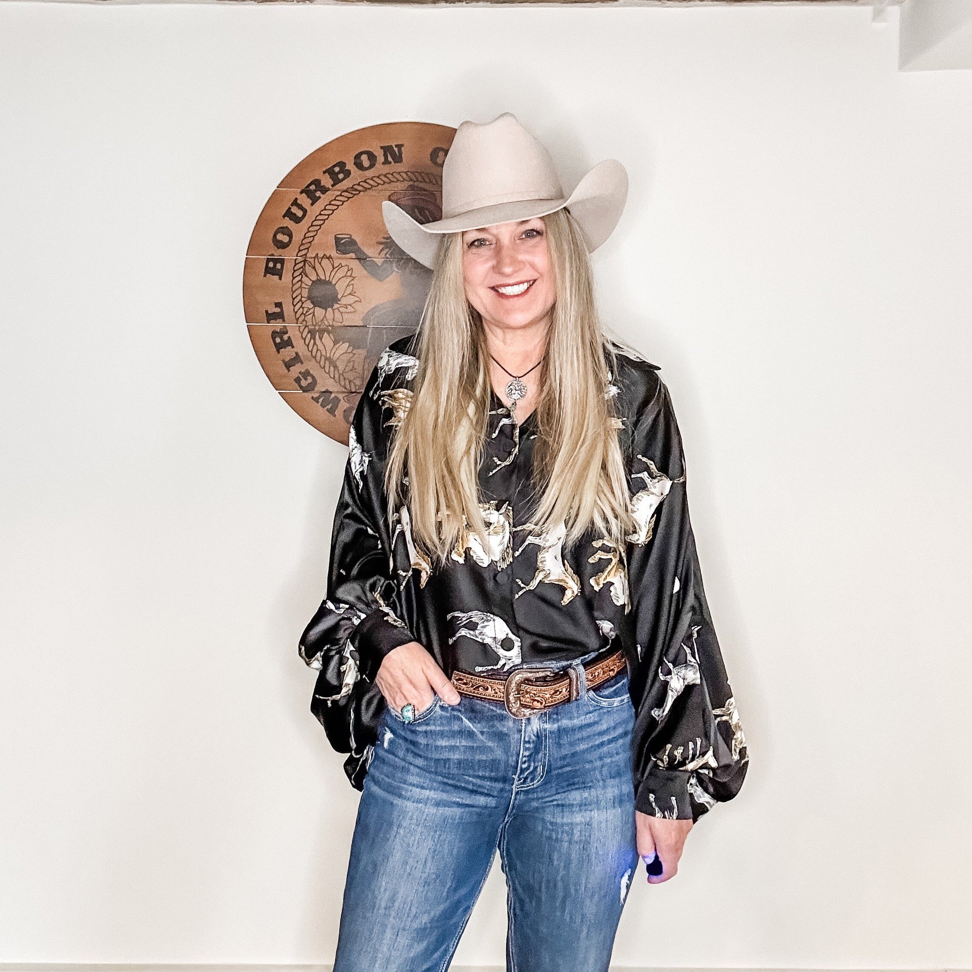 Woman in cowboy hat and patterned shirt.