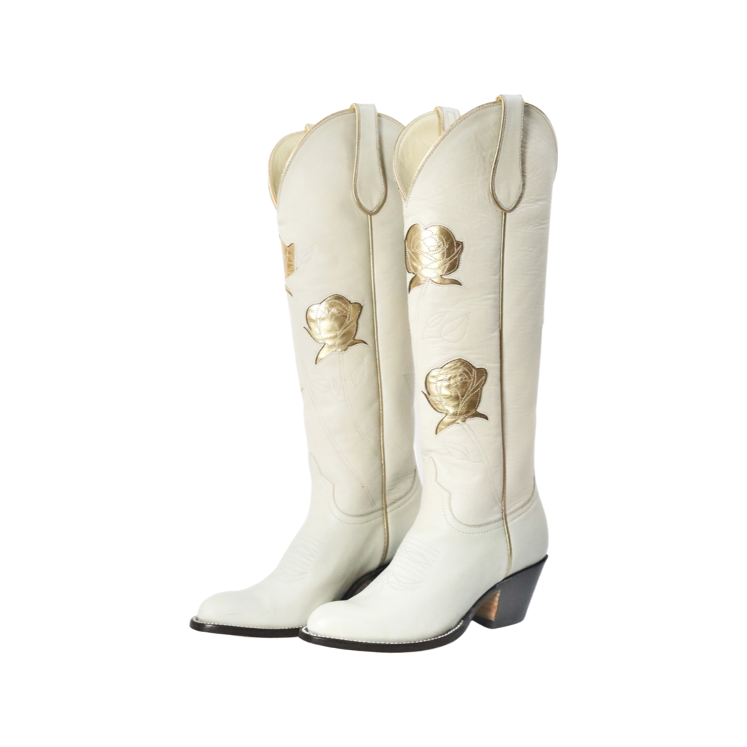Pair of white cowboy boots with gold rose accents.