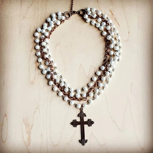 Vintage cross necklace on wooden surface.