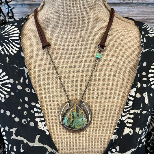 Necklace with turquoise pendant on mannequin.