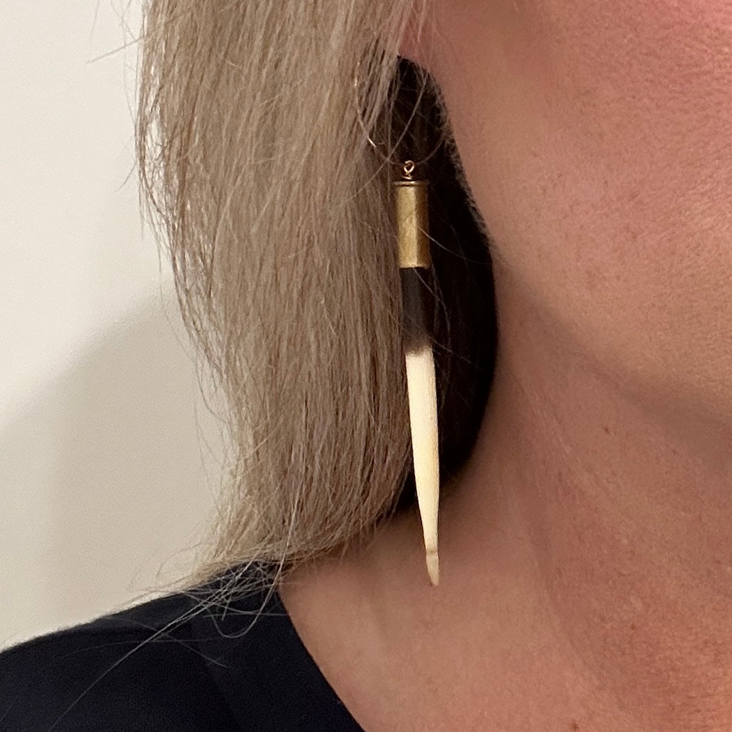 Earring made of gold and a long, white quill.