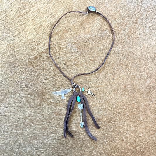 Brown necklace with charms on a textured surface.
