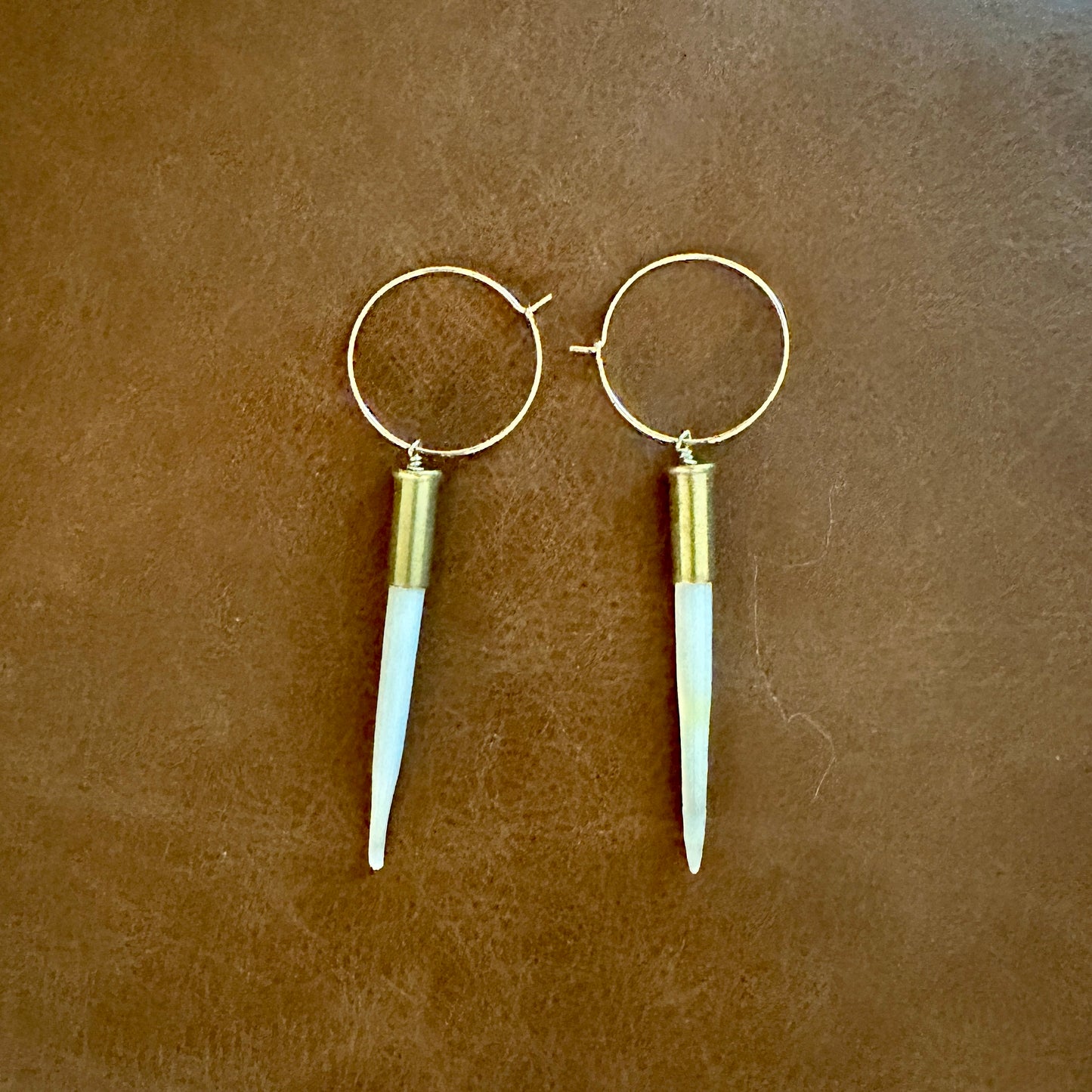Gold hoop earrings with white spike pendants.