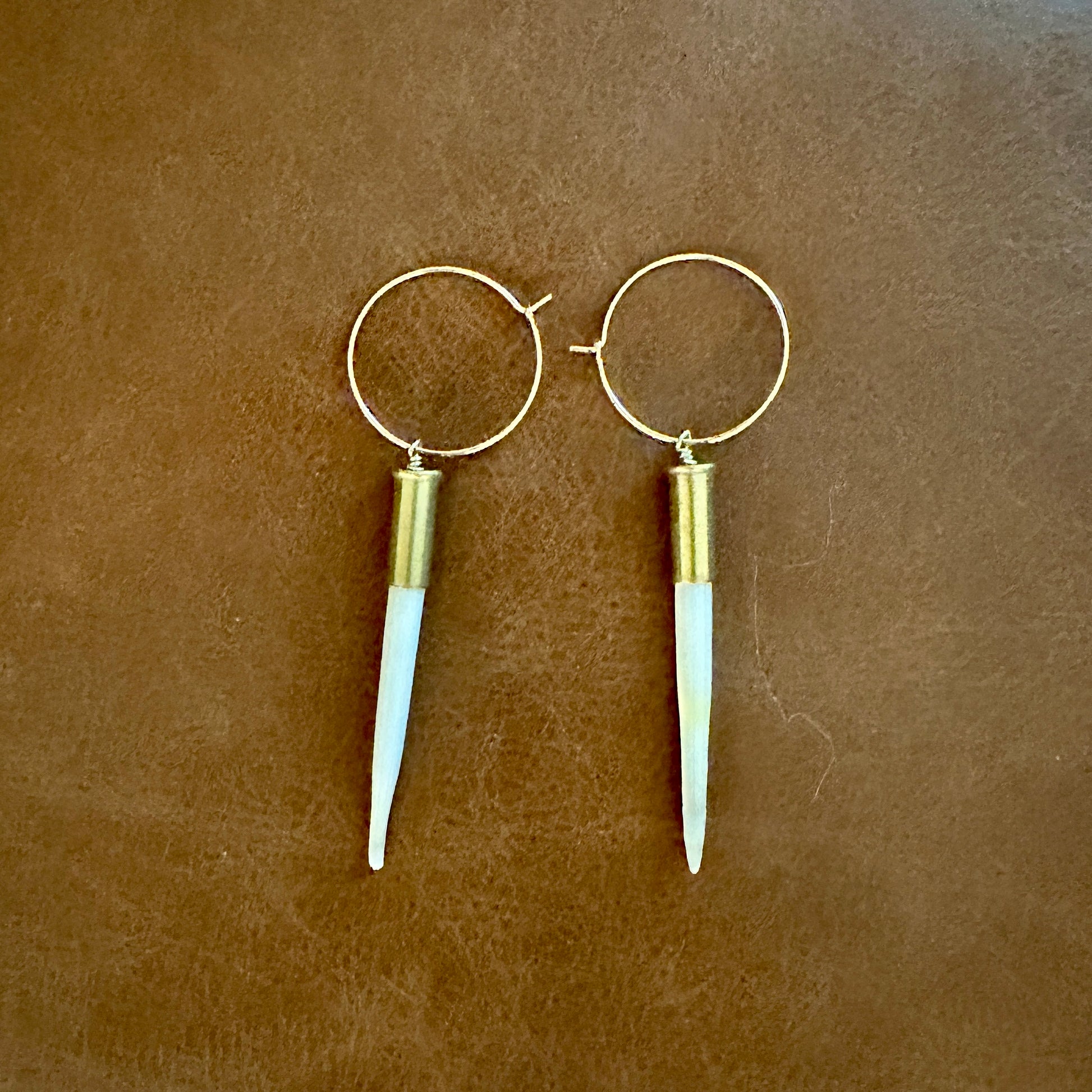 Gold hoop earrings with white spike pendants.
