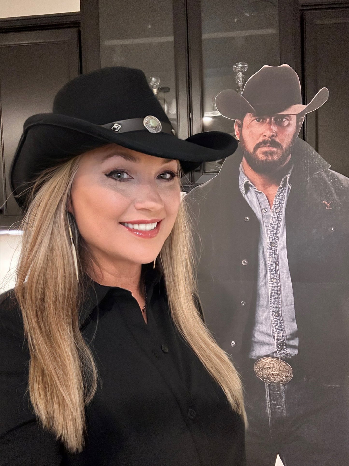 Woman in cowboy hat smiles next to a cardboard cutout of a man.